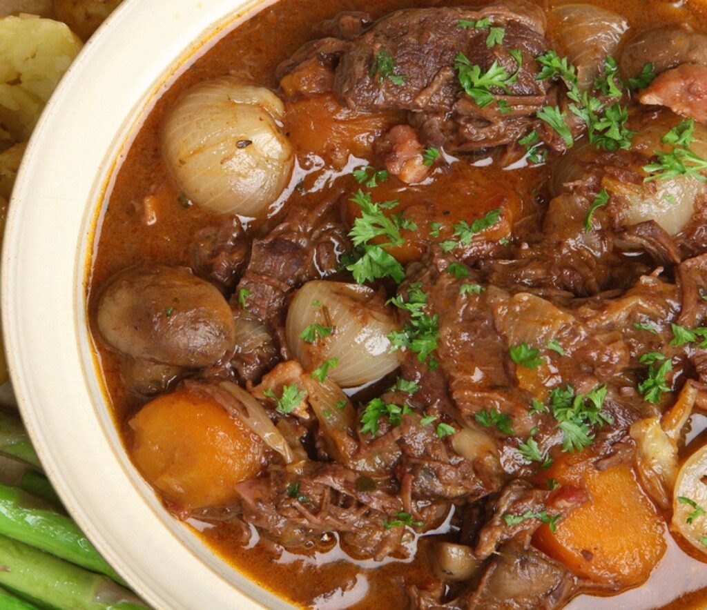  rustic bowl filled with a hearty beef stew with chunks of beef, carrots, potatoes, and onions in a brown gravy.