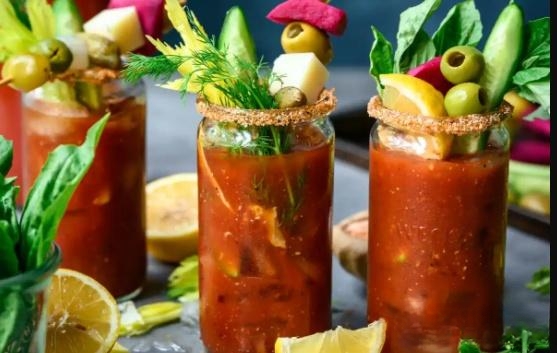 Close-up of a spicy Bloody Mary cocktail garnished with celery, olives, and various other toppings.