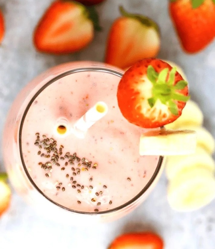 op view of a Strawberry Banana Greek Yogurt Smoothie garnished with a fresh strawberry and banana slice, with chia seeds sprinkled on top