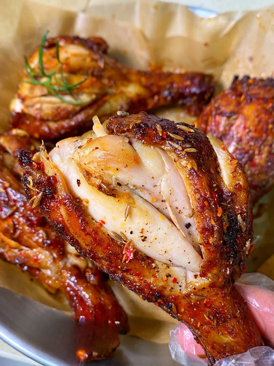 Close-up of perfectly grilled honey BBQ drumsticks, seasoned with spices and garnished with fresh herbs.