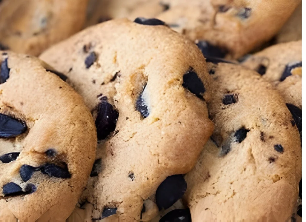 A pile of chewy chocolate chip cookies on a baking sheet.