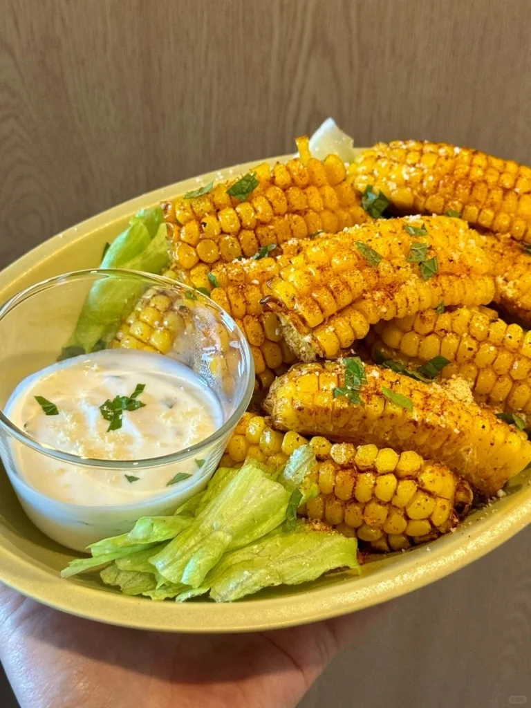 Plate of grilled corn on the cob served with creamy dipping sauce