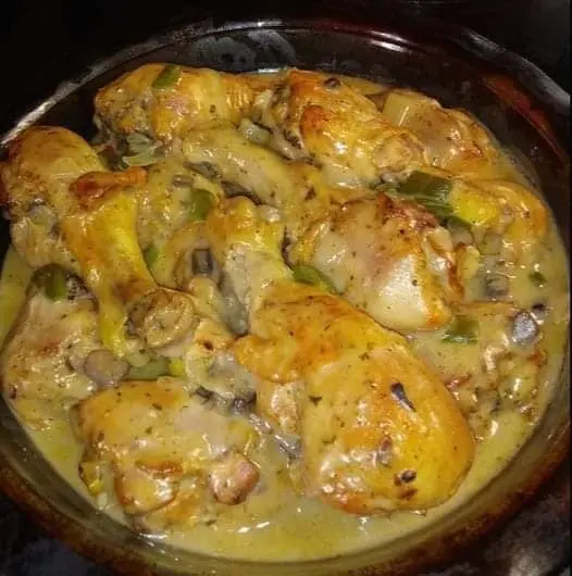 A dish of baked chicken legs covered in creamy mushroom sauce, perfectly cooked and ready to serve