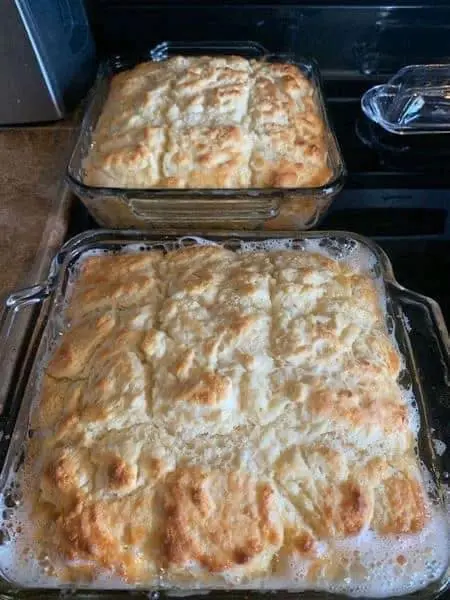 Two glass baking dishes filled with golden-brown butter swim biscuits fresh from the oven