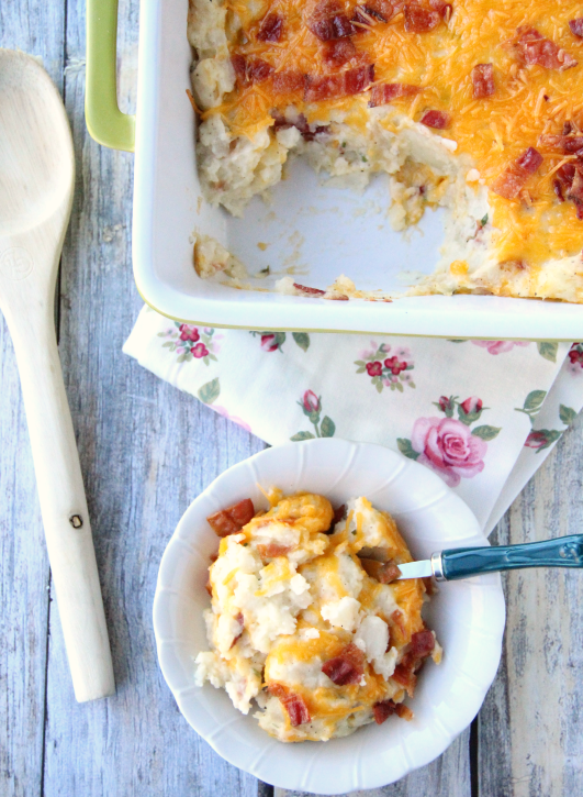 Creamy twice baked potato casserole with melted cheese and bacon bits, served in a white baking dish with a portion on a small plate