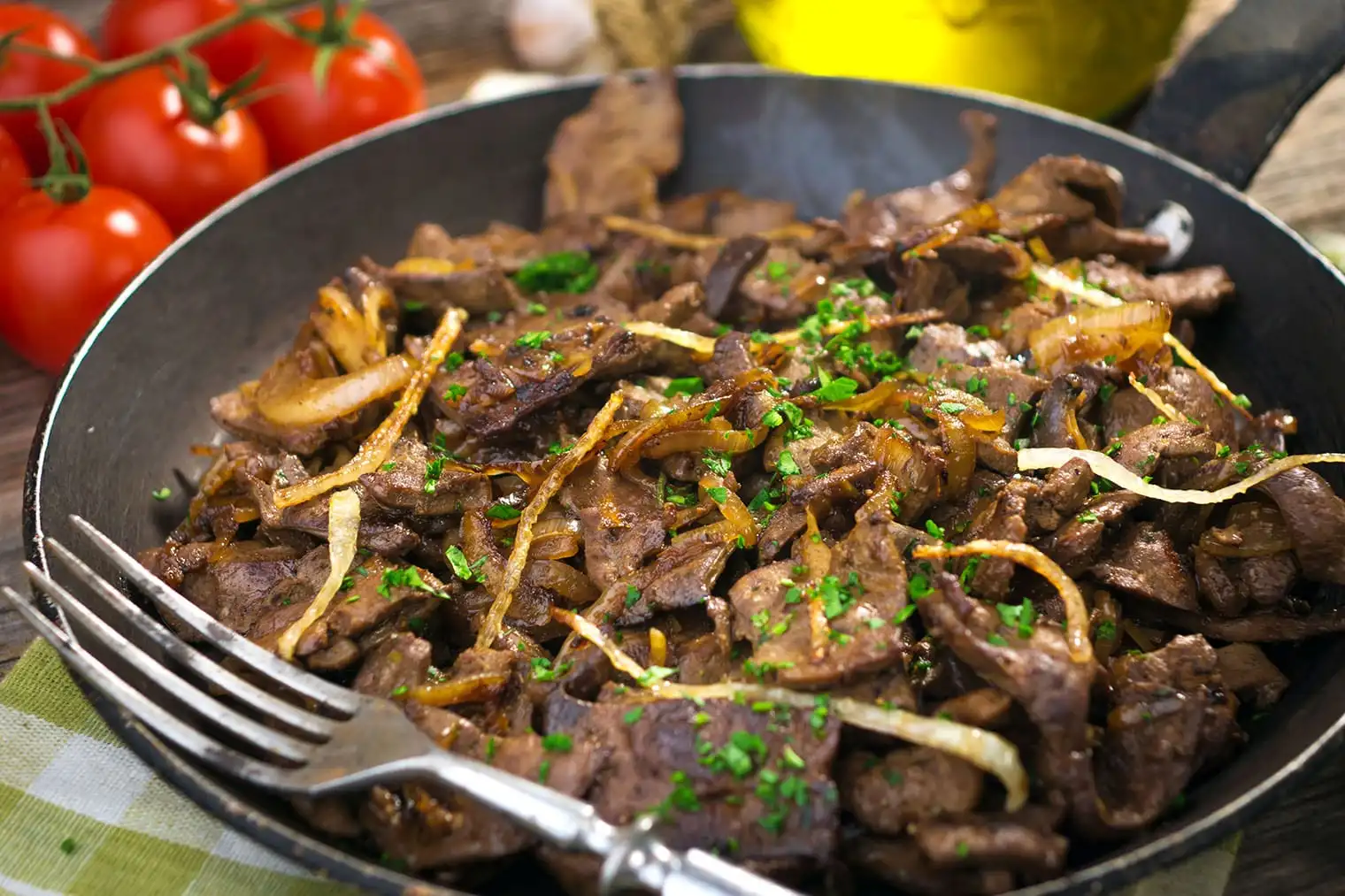 Deliciously cooked beef liver and onions garnished with fresh parsley in a skillet.