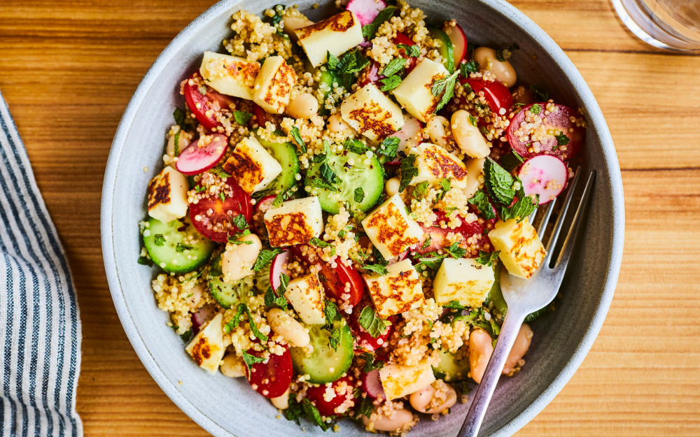 Vibrant Mediterranean quinoa salad with grilled halloumi, fresh vegetables, and herbs in a white bowl