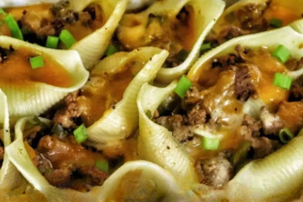 Closeup of baked Philly Cheesesteak Stuffed Shells with melted cheese, ground beef, and chopped green onions