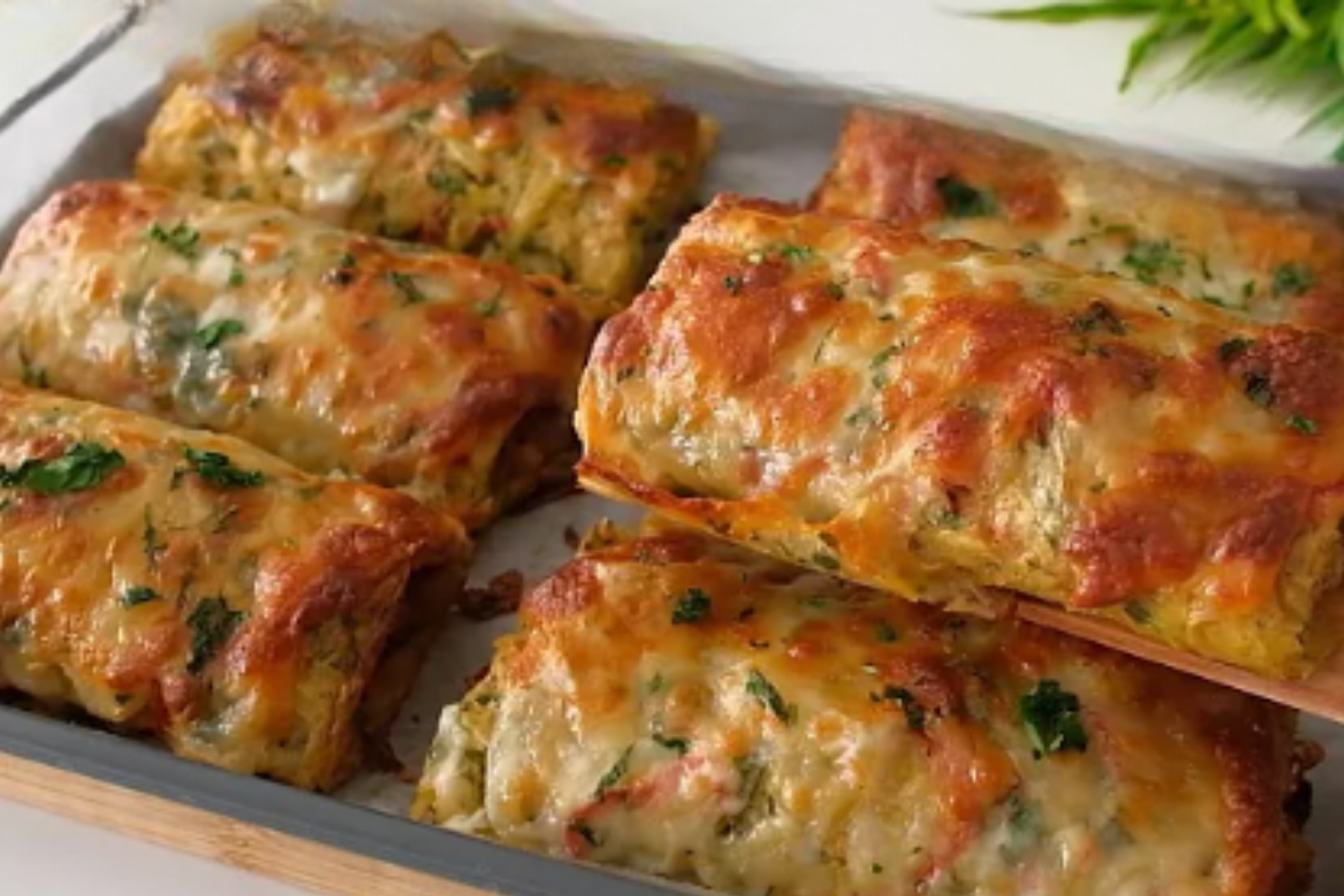 Golden brown stuffed bread rolls topped with melted cheese and fresh herbs on a baking sheet