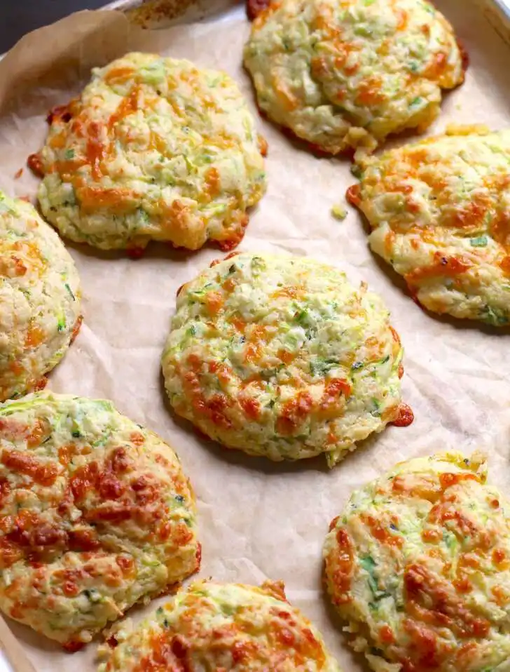 Freshly baked zucchini drop biscuits with melted cheese on parchment paper