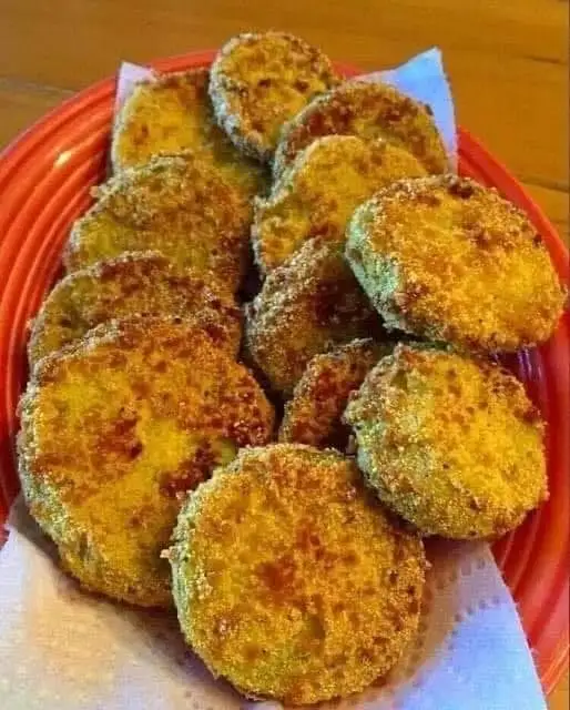 Golden-brown, crispy fried green tomato slices on an orange plate