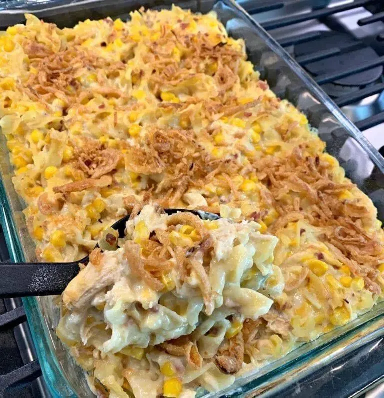 Cheesy chicken noodle casserole with corn and crispy onion topping in a glass baking dish