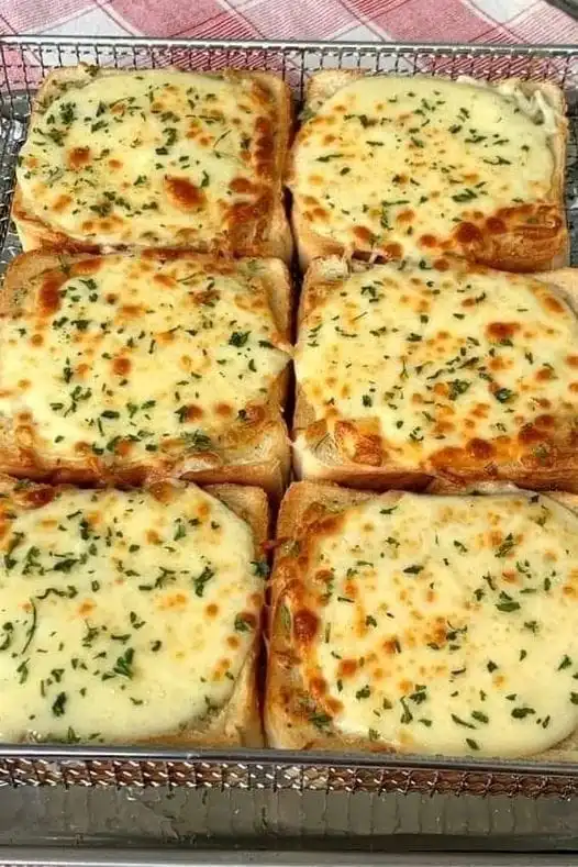 Six slices of golden brown Cheesy Texas Toast topped with melted cheese and herbs on a baking sheet