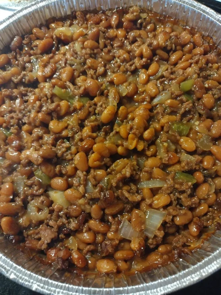 Close-up of hearty cowboy baked beans with ground beef and onions in a foil pan