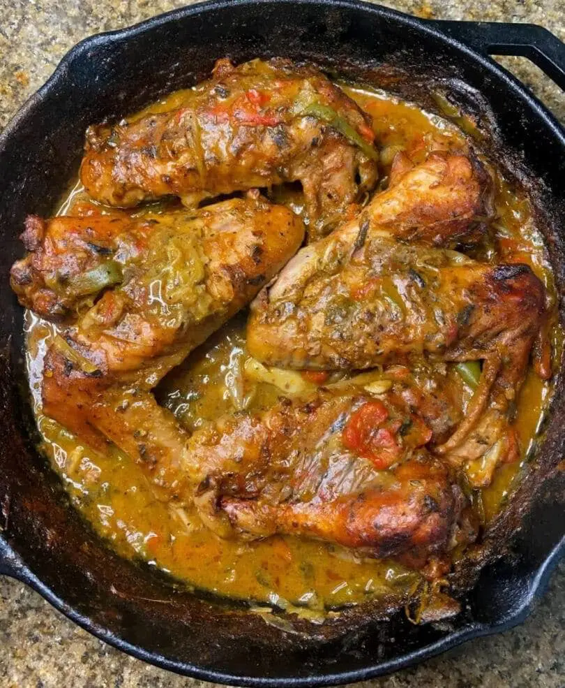 Smothered turkey wings in a savory gravy with vegetables in a cast iron skillet