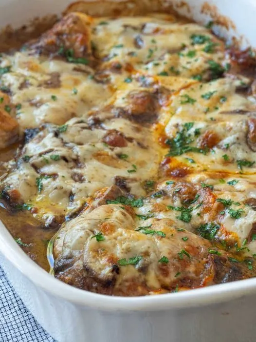 Chicken Gloria Casserole in a white baking dish, topped with melted cheese and fresh herbs