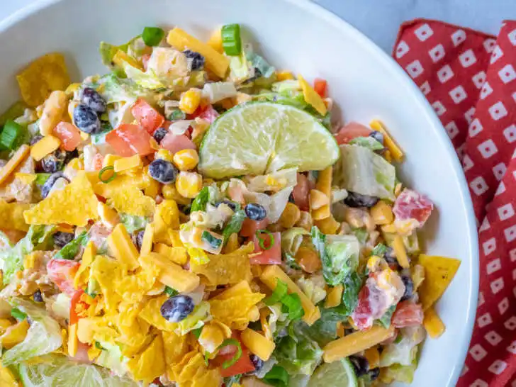 A vibrant black bean taco bowl filled with colorful ingredients like avocado, corn, tomatoes, and cilantro, served in a bowl with tortilla chips.