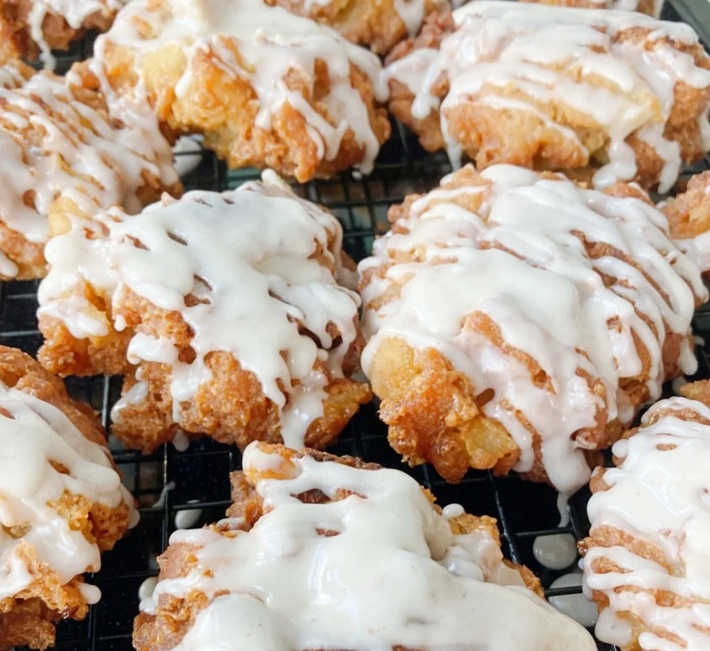 Freshly fried caramel apple fritters drizzled with sweet glaze on a cooling rack