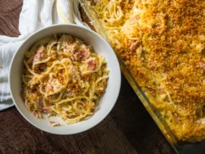 Creamy Chicken Cordon Bleu Tetrazzini in a white bowl next to baking dish with golden breadcrumb topping