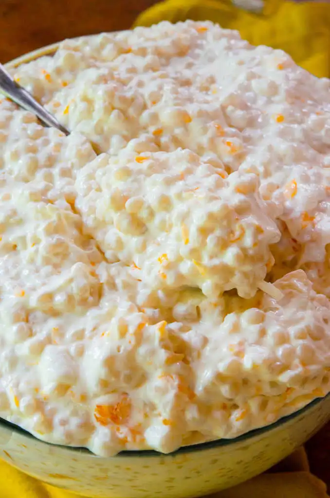 Creamy Frog Eye Salad with tiny pasta pearls and orange fruit bits in a glass bowl