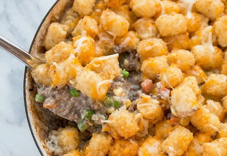 Close-up of a cheesy tater tot casserole with golden crispy tots, melted cheese, and a creamy beef and vegetable filling