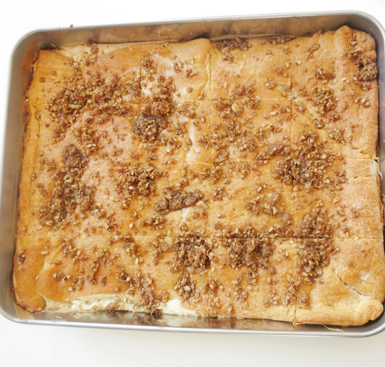 Freshly baked Kentucky Cheesecake Bars in a baking pan, topped with golden brown pecan crumble