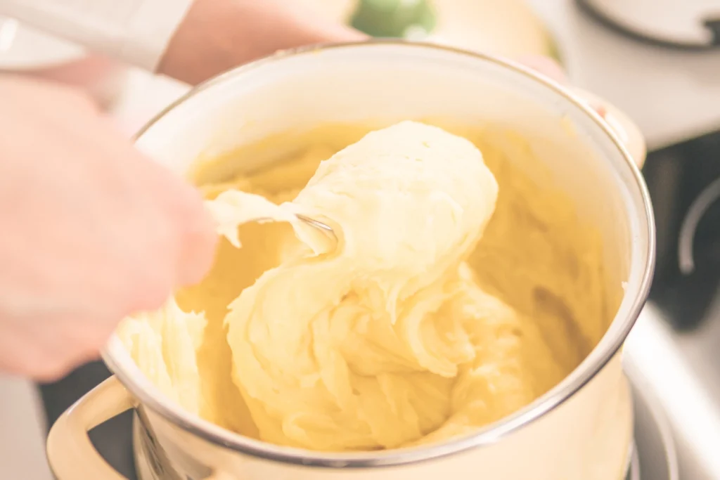 Creamy mashed potatoes being whipped in a stainless steel mixing bowl