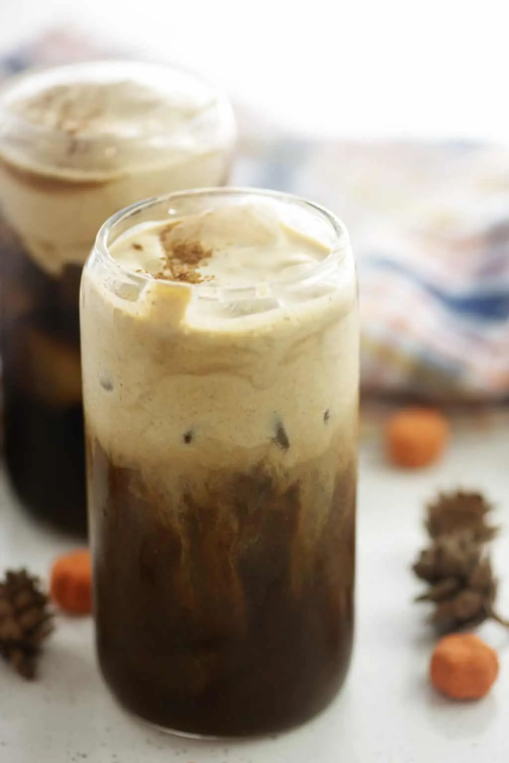 Layered pumpkin cream cold brew coffee in a glass jar with fall decorations